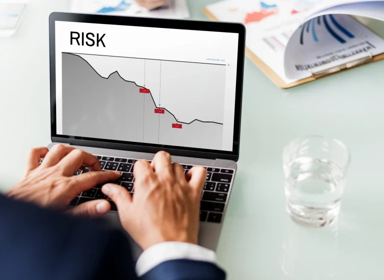 Hands typing on a laptop showing a risk line chart
