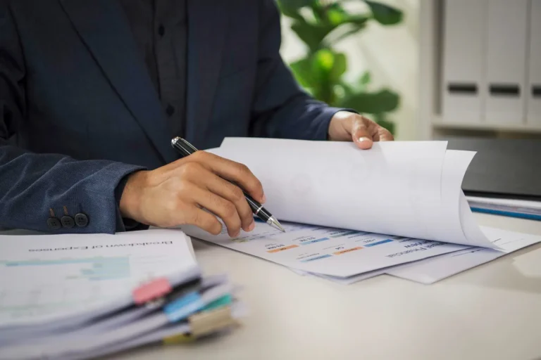 Banker reviewing printed trade documents with a pen